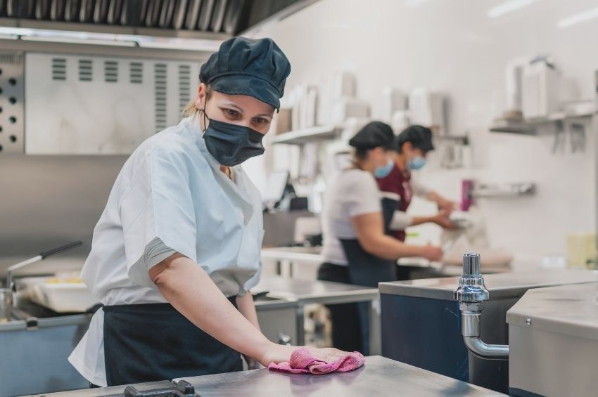 Food handler cleaning and sanitizing a food contact surface