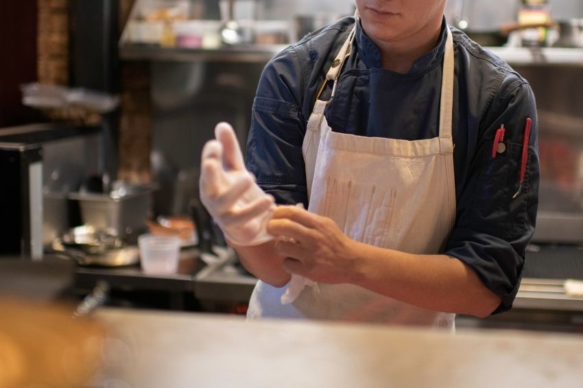 Food handler putting on gloves before starting work