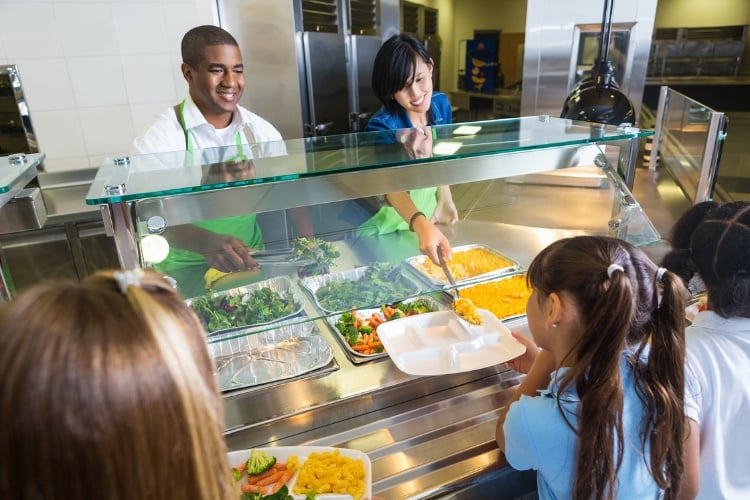 Two adults serving lunch at a school