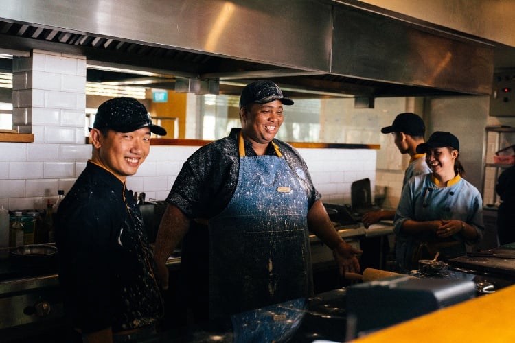 Smiling food handlers in a kitchen practicing food safety