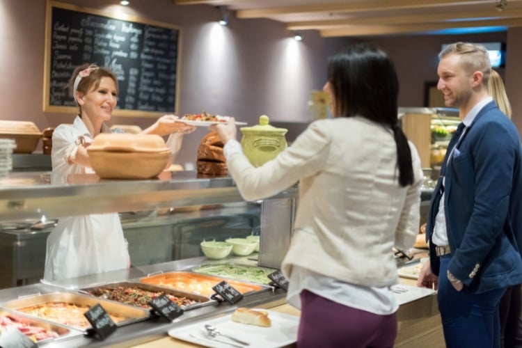 Foodservice worker serving customers at a cafeteria