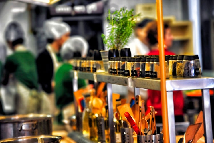 Spices and kitchen utensils with food handlers in hair nets in the background