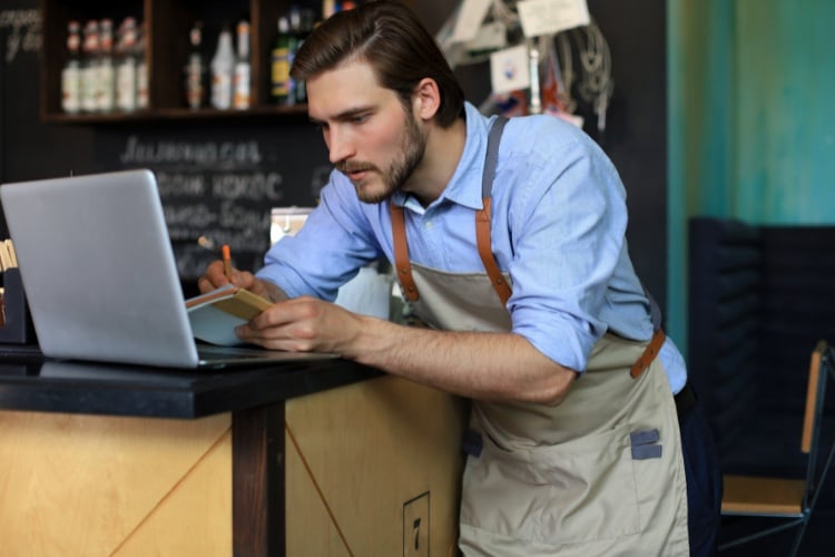 Food manager taking notes while looking at a computer